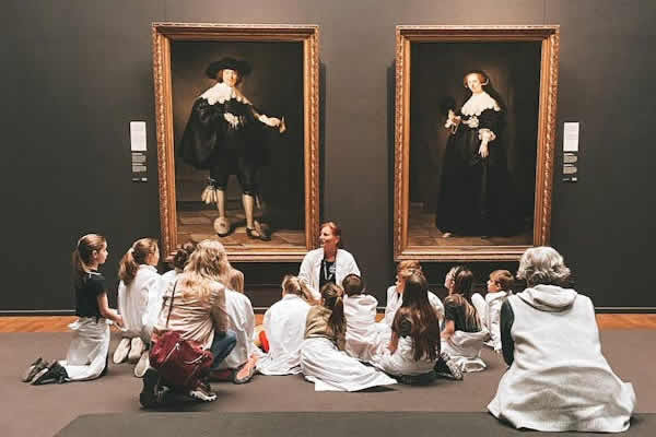 grupo de niños frente a dos pinturas en museo de arte con dos guías